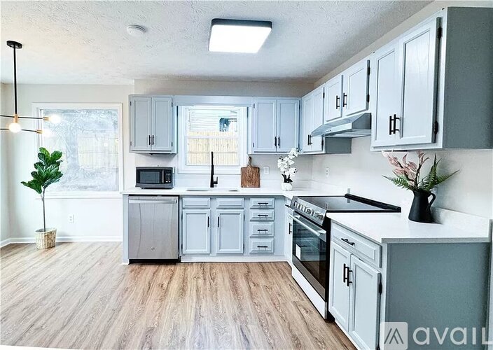 A kitchen with grey cabinets and a wooden floor.