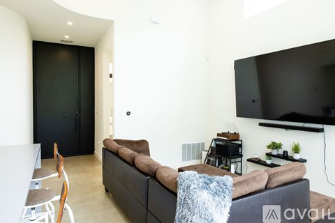 A living room with a brown couch and a flat screen TV mounted on the wall.