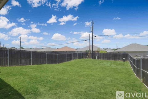 A backyard with a fence and a grassy area.