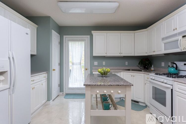 A kitchen with white appliances and a table with a vase of flowers on it.