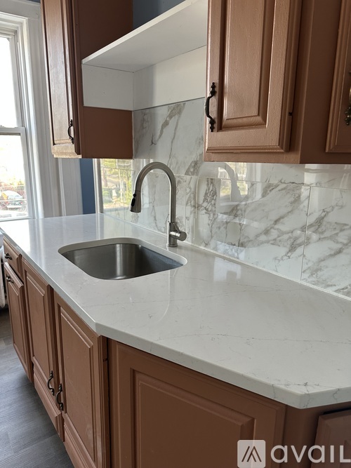 A kitchen with brown cabinets and a marble countertop.