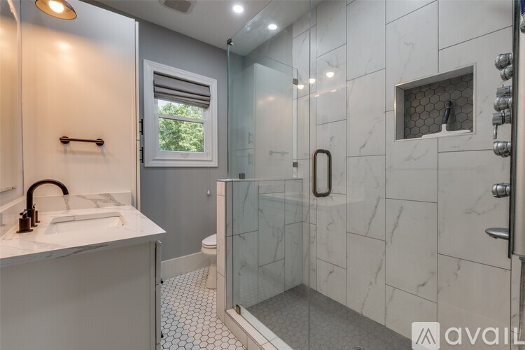 A bathroom with a marble tile shower and a white sink.