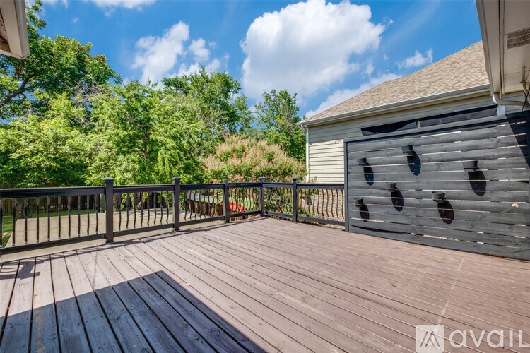 A wooden deck with a railing and a shed in the background.