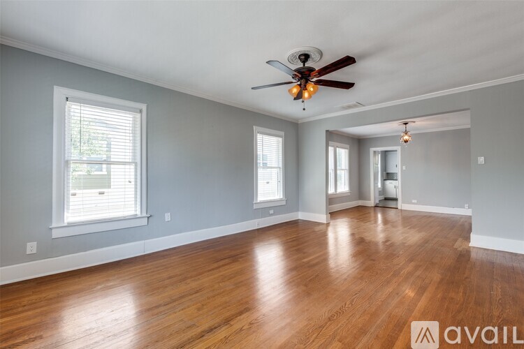 A spacious room with wooden floors and a ceiling fan.