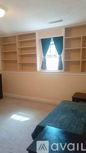 A bedroom with a bed and a window with blue curtains.
