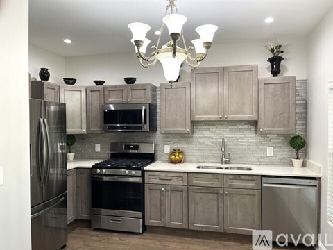 A modern kitchen with a stainless steel refrigerator and a black stove top oven.