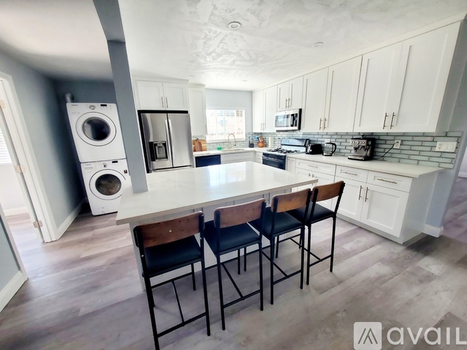 A kitchen with a white countertop and a washer and dryer stacked on it.