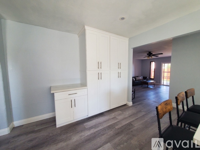 A room with a cabinet, a chair and a ceiling fan.