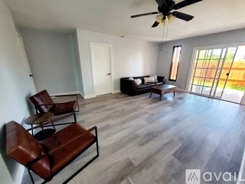 A living room with a black couch and a ceiling fan.