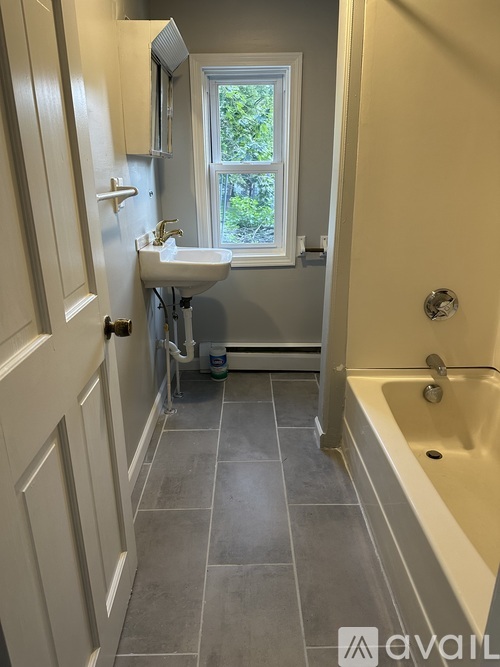A bathroom with a tub, sink, and window.
