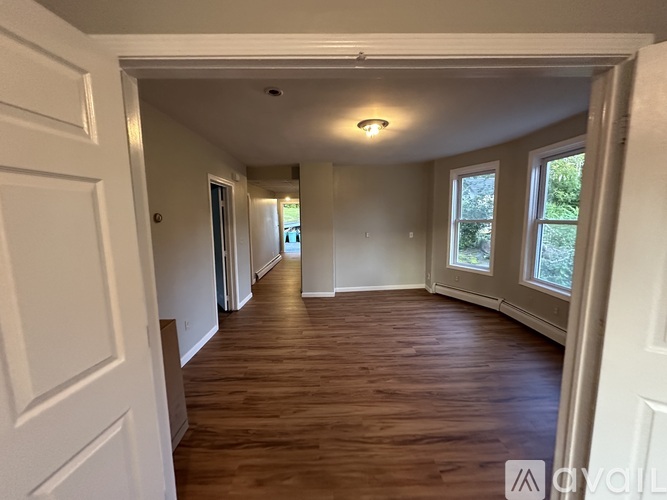 A long hallway with wood floors and white walls.