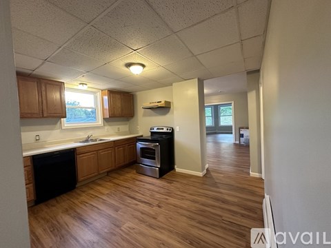 A kitchen with wooden floors and a black dishwasher.