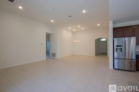 A spacious kitchen with a refrigerator and a stove top oven.