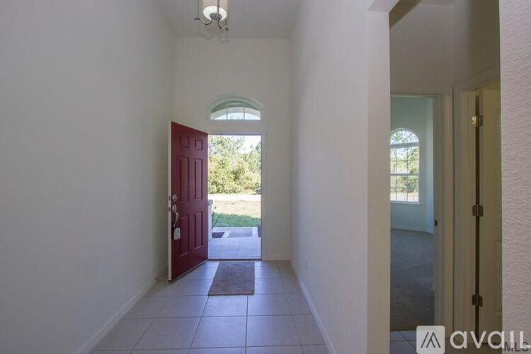 A hallway with a red door and a window.