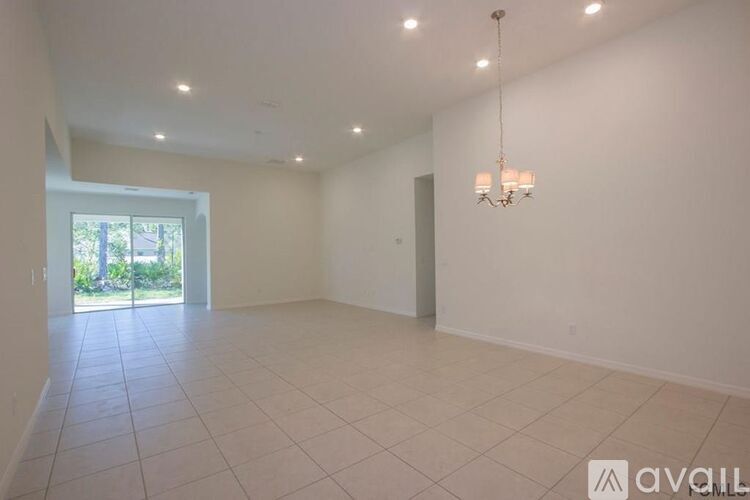 A spacious room with white walls and a chandelier hanging from the ceiling.