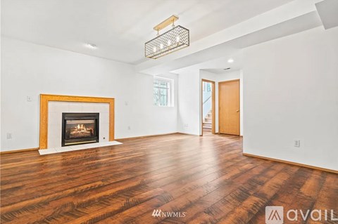 A large empty room with a fireplace and wooden floors.