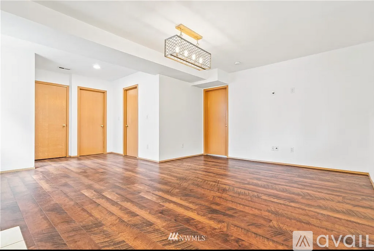 A room with wooden floors and three doors.