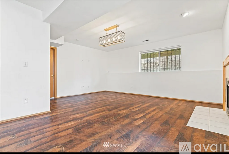 A room with wooden flooring and a window with blinds.