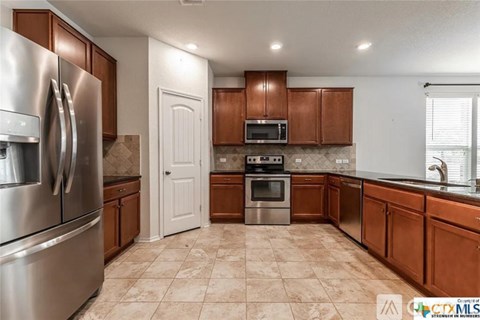 A kitchen with brown cabinets and a stainless steel refrigerator.