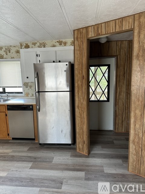 A kitchen with a stainless steel refrigerator and wooden cabinets.