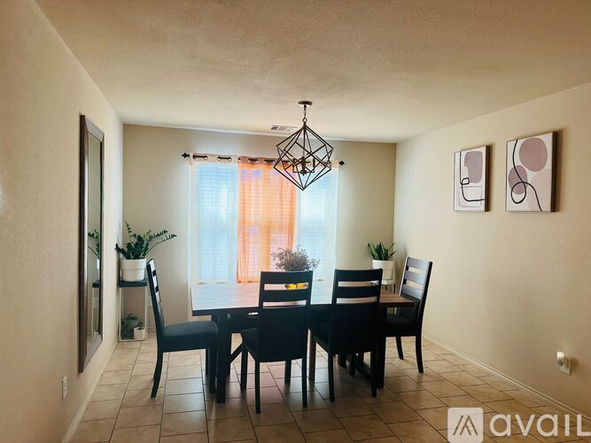 A dining room with a table set for four and a chandelier hanging from the ceiling.