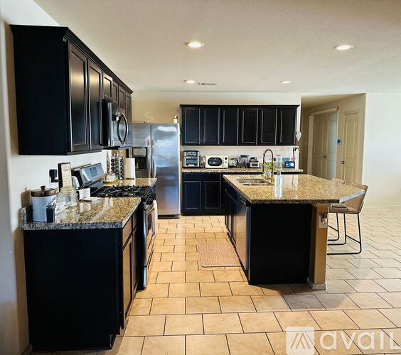 A kitchen with black cabinets and granite countertops.