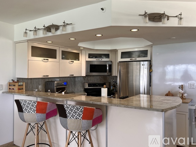 A modern kitchen with a center island and bar stools.