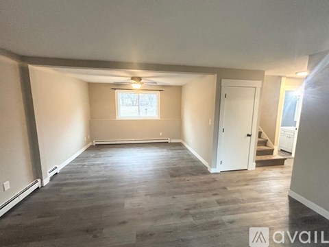A spacious room with a window and a door leading to another room.