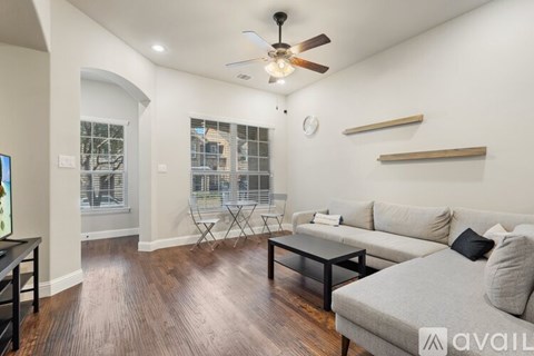 A living room with a grey couch and a ceiling fan.