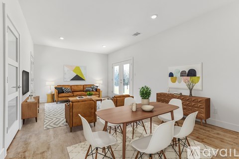 A modern living room with a wooden dining table and white chairs.