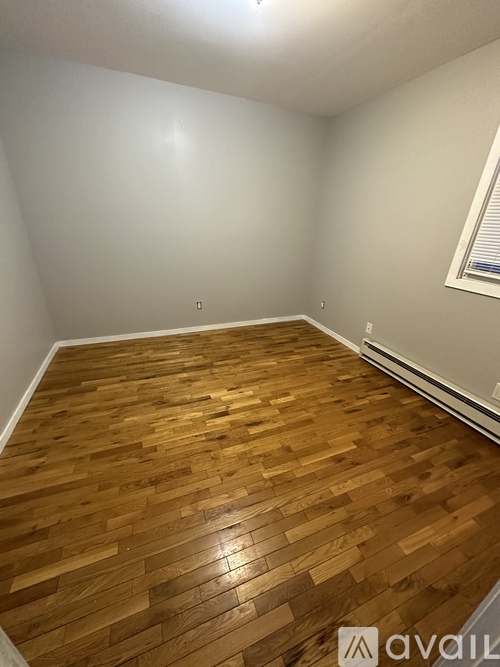 A room with wooden flooring and a window with blinds.