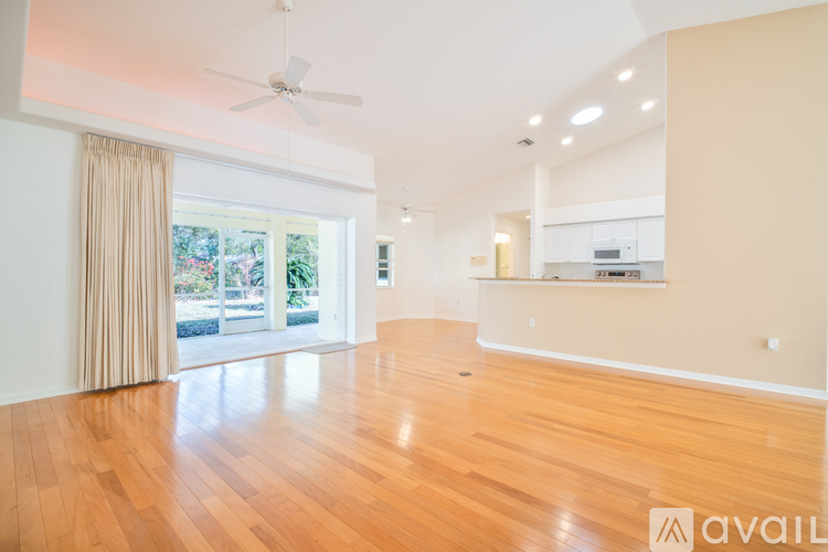 A spacious room with wooden floors and a ceiling fan.