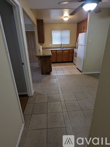 A kitchen with a refrigerator, sink, and cabinets.