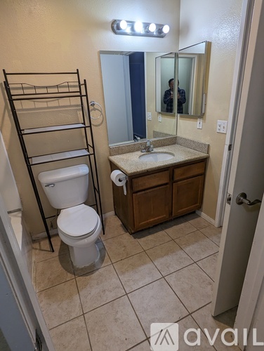 A bathroom with a toilet, sink, and mirror.