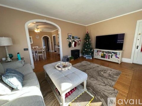 A living room with a grey sofa and a television on a white stand.