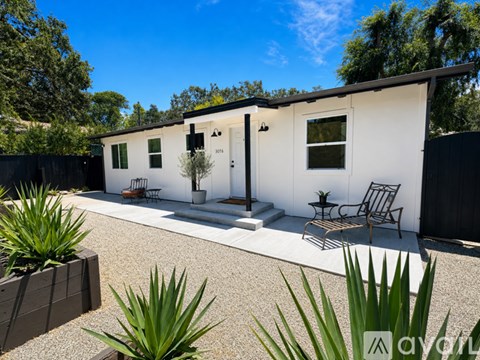 A white house with a black fence and a small garden in front.