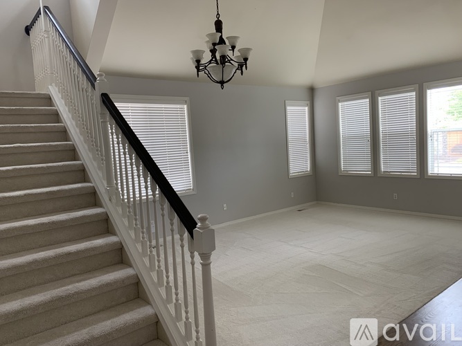 A living room with a staircase and a chandelier.