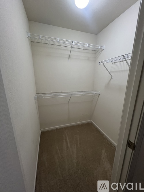 A small, empty closet with a white door and shelves.