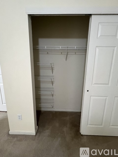 A white closet with a door and shelves.