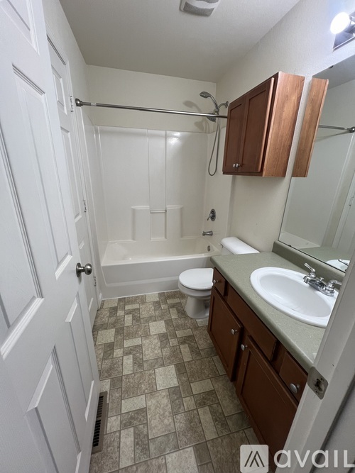 A bathroom with a white door, a white toilet, a white sink, and a white bathtub.