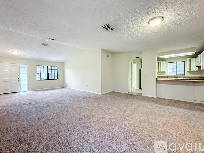 A spacious room with a carpeted floor and a window.