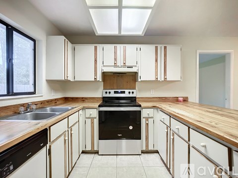 A kitchen with a black stove top oven and white cabinets.