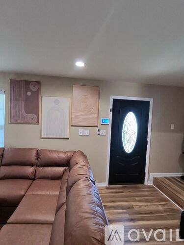 A living room with a brown leather couch and a door with a circular window.