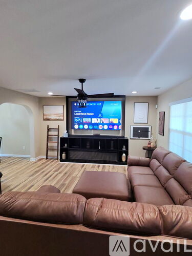 A modern living room with a brown leather sofa and a large television screen.