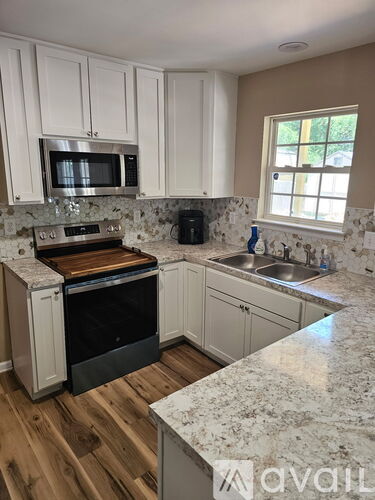 A kitchen with white cabinets and a granite countertop.
