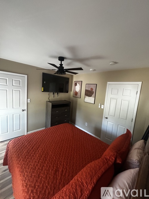 A bedroom with a bed covered in a red comforter.
