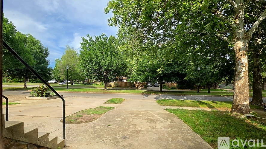 A park with a concrete pathway, trees, and a staircase.