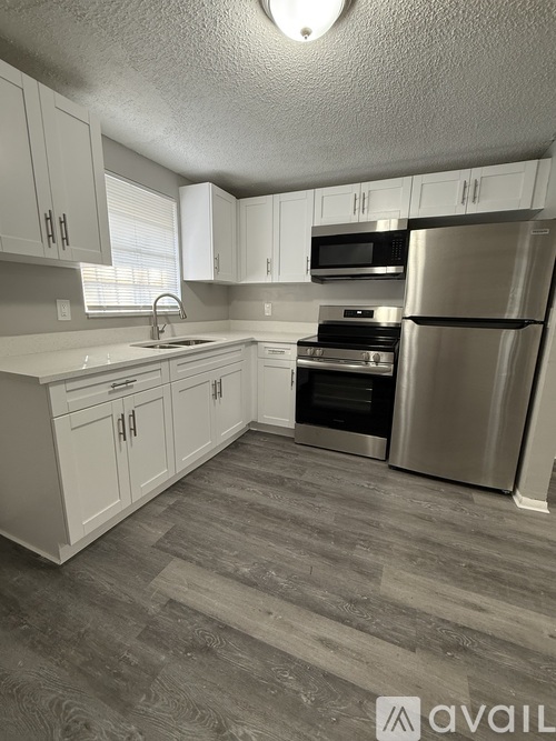 A kitchen with white cabinets and a stainless steel refrigerator.