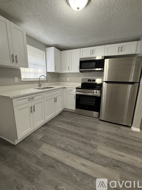 A kitchen with white cabinets and a stainless steel refrigerator.