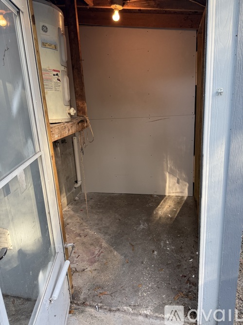 A dirty, unfinished basement with a white door and a white refrigerator.